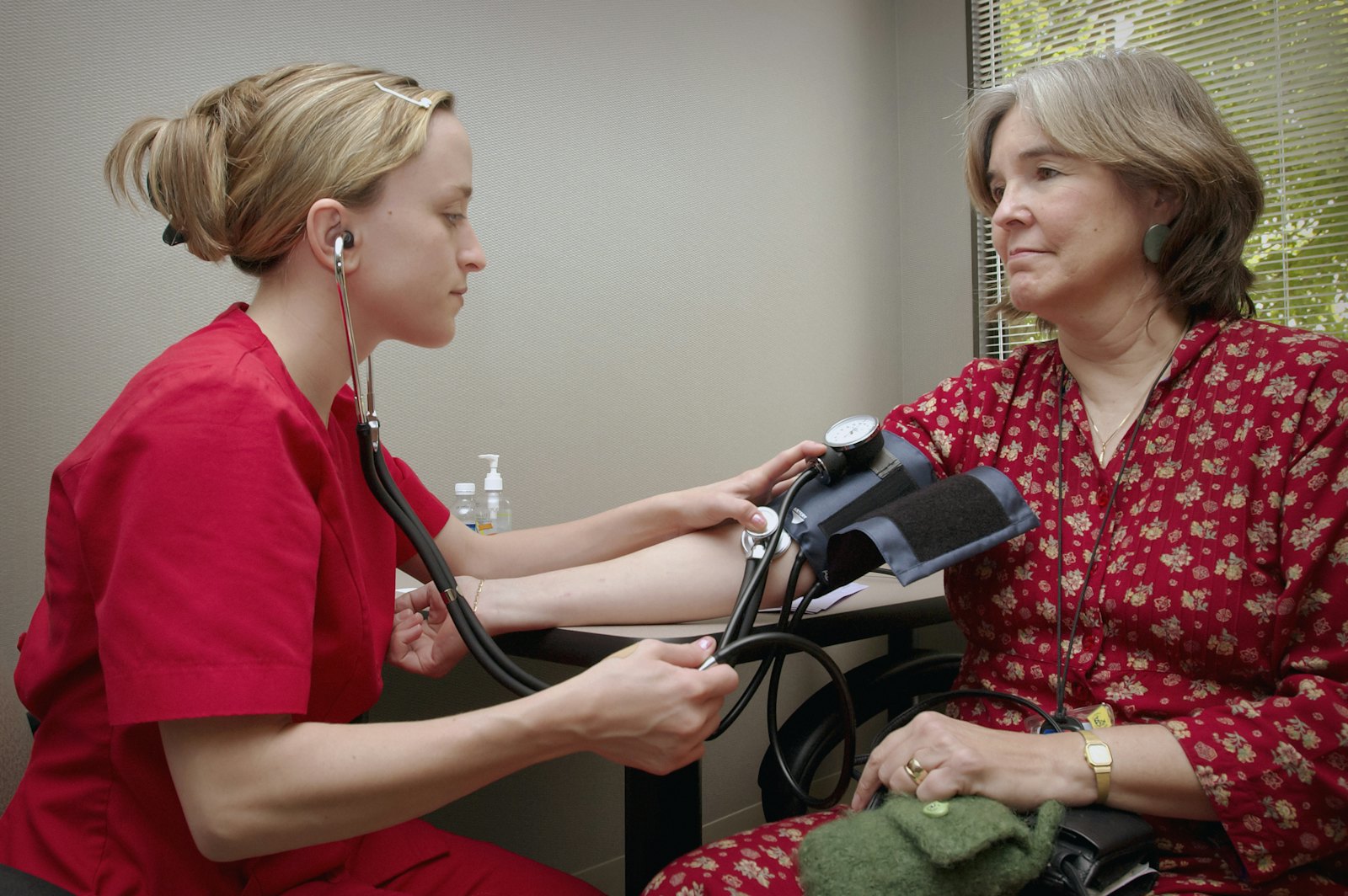 A clinician listens to a patient's heart with a stethoscope.
